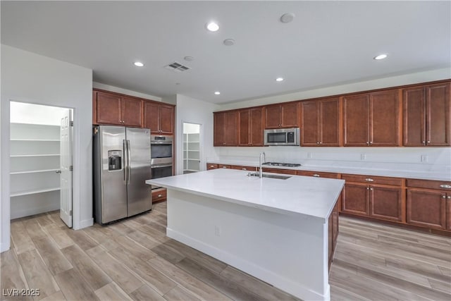 508 Cadence View Way, Henderson, NV 89011 - kitchen with appliances with stainless steel finishes, a sink, light countertops, light wood-style floors, and an island with sink