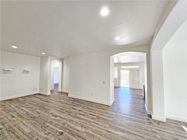 3829 N Mayfield Ranch Rd, Pahrump, NV 89060 - empty room featuring arched walkways, wood finished floors, a textured ceiling, recessed lighting, and baseboards