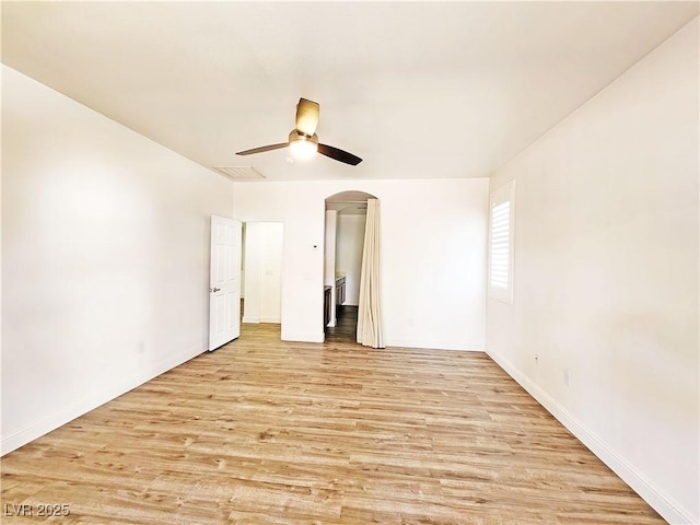 3829 N Mayfield Ranch Rd, Pahrump, NV 89060 - spare room with light wood-style floors, a ceiling fan, arched walkways, and baseboards