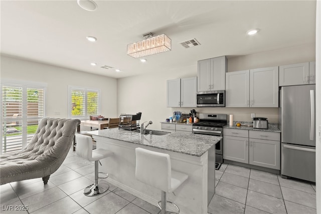 9161 Rolling Sky Dr, Las Vegas, NV 89178 - kitchen featuring stainless steel appliances, a sink, light tile patterned floors, light stone countertops, and an island with sink