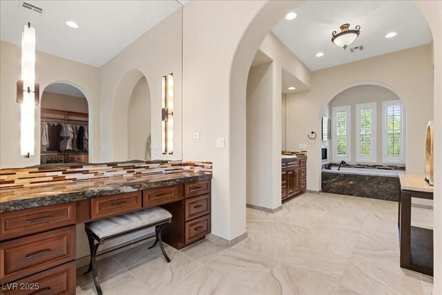 300 N Royal Ascot Dr, Las Vegas, NV 89144 - bathroom with vanity, a garden tub, decorative backsplash, recessed lighting, and a walk in closet