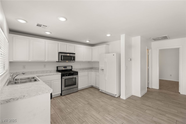 6480 Chebec St, North Las Vegas, NV 89084 - kitchen with stainless steel appliances, light countertops, white cabinets, light wood-style flooring, and recessed lighting