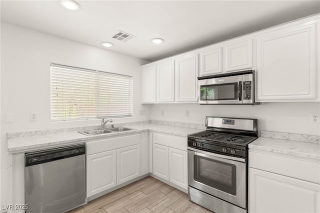 6480 Chebec St, North Las Vegas, NV 89084 - kitchen featuring stainless steel appliances, white cabinets, recessed lighting, wood tiled floors, and light stone counters