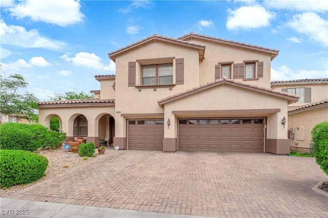 9614 Stonily Ln, Las Vegas, NV 89178 - mediterranean / spanish-style house featuring an attached garage, a tile roof, stucco siding, and decorative driveway