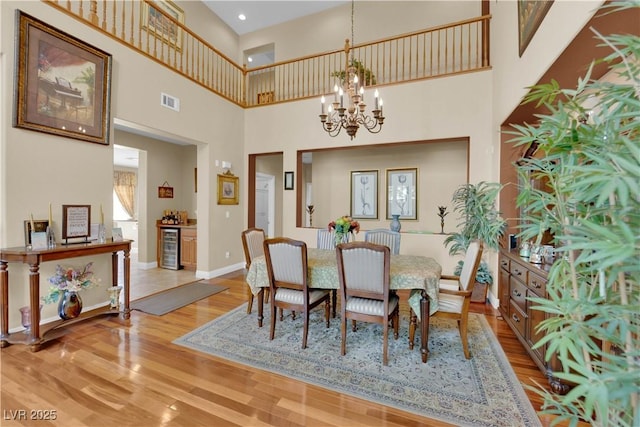 9614 Stonily Ln, Las Vegas, NV 89178 - dining room with a towering ceiling, a chandelier, wood finished floors, baseboards, and wine cooler