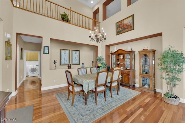 9614 Stonily Ln, Las Vegas, NV 89178 - dining space with washer / clothes dryer, a high ceiling, light wood-style floors, a chandelier, and baseboards