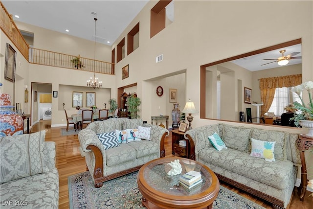 9614 Stonily Ln, Las Vegas, NV 89178 - living room featuring a chandelier, wood finished floors, washer / clothes dryer, a high ceiling, and a ceiling fan