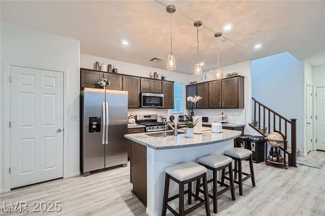 1328 Graphite Ave, Henderson, NV 89002 - kitchen featuring stainless steel appliances, dark brown cabinets, a sink, light wood-type flooring, and a kitchen bar