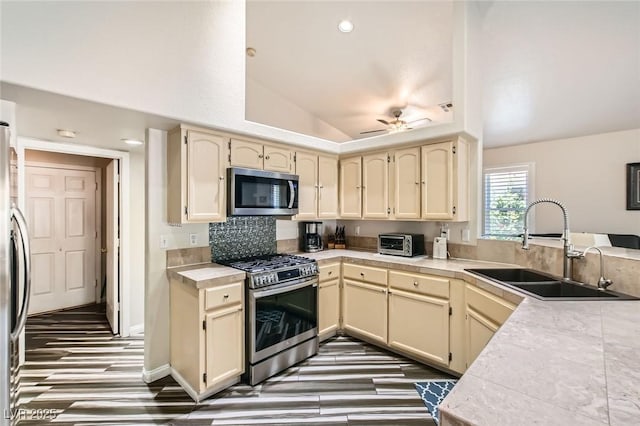 5489 Royal Vista Ln, Las Vegas, NV 89149 - kitchen featuring appliances with stainless steel finishes, a sink, vaulted ceiling, cream cabinetry, and light countertops