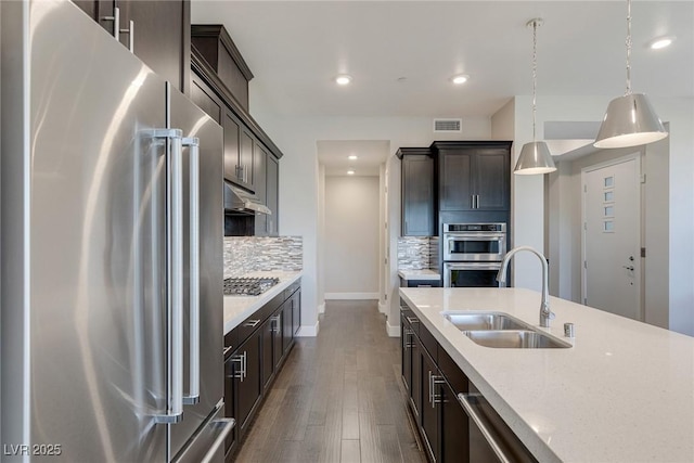 11280 Granite Ridge Dr Unit 1009, Las Vegas, NV 89135 - kitchen featuring appliances with stainless steel finishes, a sink, tasteful backsplash, under cabinet range hood, and baseboards