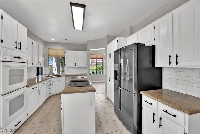 2714 Bridgepointe Dr, Las Vegas, NV 89121 - kitchen with appliances with stainless steel finishes, a sink, a center island, backsplash, and white cabinets