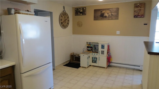 18 Connors Ct, Ely, NV 89301 - kitchen featuring freestanding refrigerator, a baseboard heating unit, a wainscoted wall, and light flooring