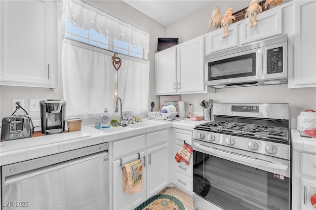 1011 Dancing Vines Ave, Las Vegas, NV 89183 - kitchen with appliances with stainless steel finishes, white cabinetry, and tile counters