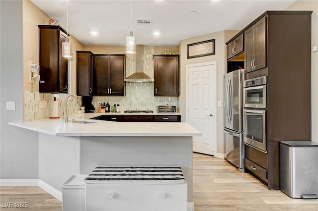 1425 Overseer Ave, Henderson, NV 89074 - kitchen with stainless steel appliances, a sink, wall chimney exhaust hood, dark brown cabinetry, and a peninsula