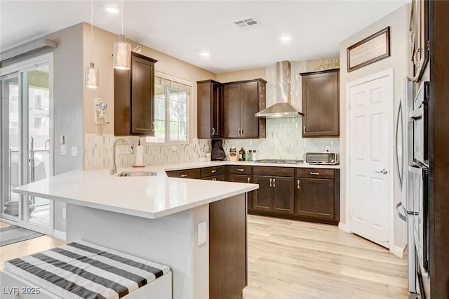 1425 Overseer Ave, Henderson, NV 89074 - kitchen featuring wall chimney exhaust hood, a peninsula, a sink, dark brown cabinetry, and light wood-style flooring