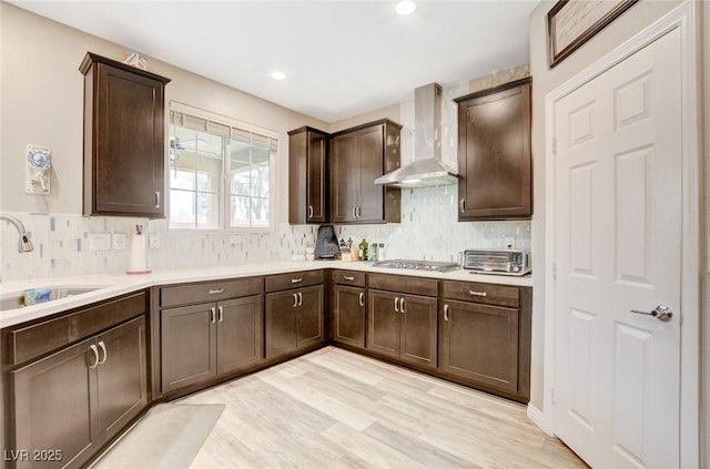 1425 Overseer Ave, Henderson, NV 89074 - kitchen featuring wall chimney range hood, a sink, dark brown cabinets, stainless steel gas stovetop, and tasteful backsplash