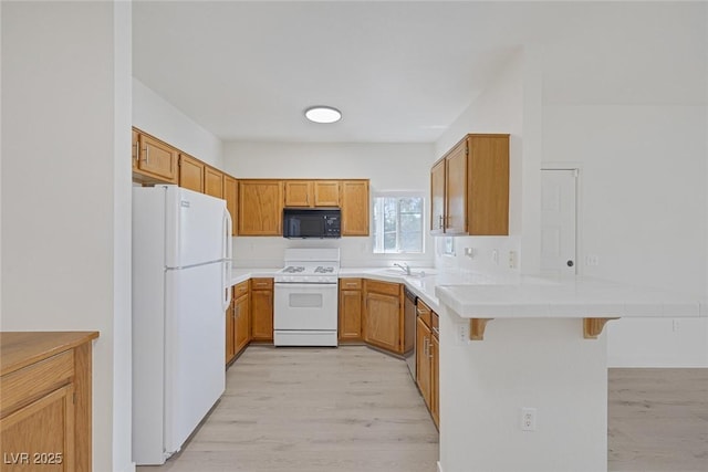 1830 N Buffalo Dr Unit 2024, Las Vegas, NV 89128 - kitchen featuring white appliances, a peninsula, a sink, light wood-type flooring, and a kitchen bar