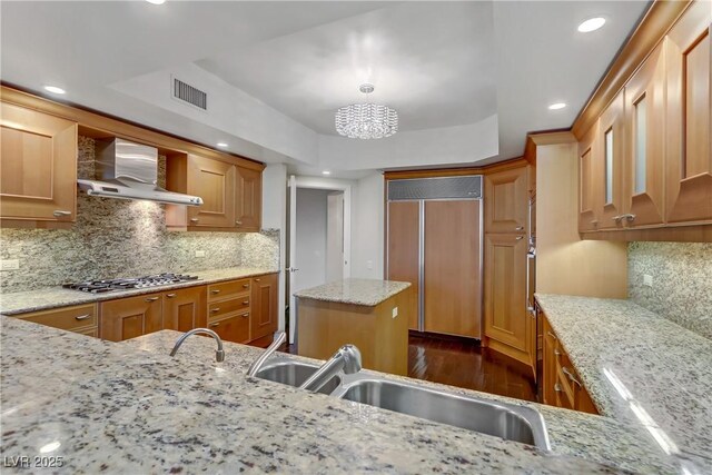 2777 Paradise Rd Unit 2001, Las Vegas, NV 89109 - kitchen with paneled built in fridge, wall chimney exhaust hood, stainless steel gas cooktop, dark wood finished floors, and a sink