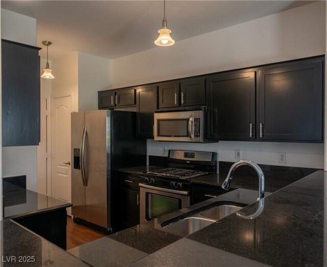 5256 Harvest Breeze Rd, Las Vegas, NV 89118 - kitchen with stainless steel appliances, a sink, dark stone countertops, hanging light fixtures, and dark cabinetry