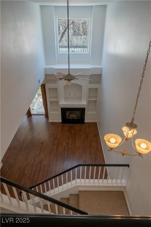 5256 Harvest Breeze Rd, Las Vegas, NV 89118 - stairway with a high ceiling, wood finished floors, a fireplace, and a chandelier