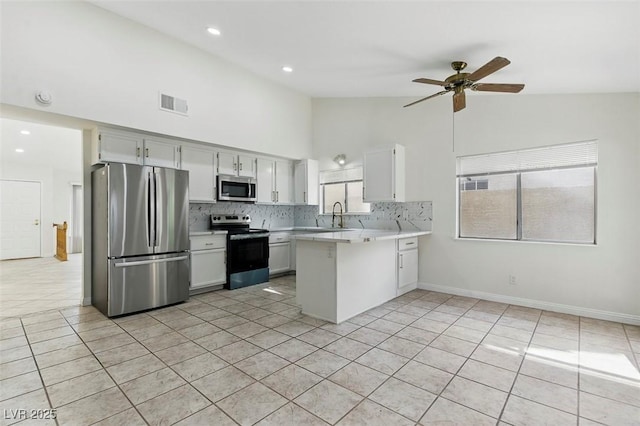 9116 Cypress Point Way, Las Vegas, NV 89117 - kitchen featuring stainless steel appliances, a peninsula, light countertops, light tile patterned floors, and high vaulted ceiling