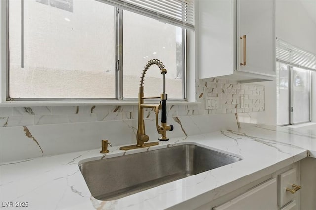 9116 Cypress Point Way, Las Vegas, NV 89117 - kitchen view of a sink, backsplash, white cabinetry, and light stone countertops
