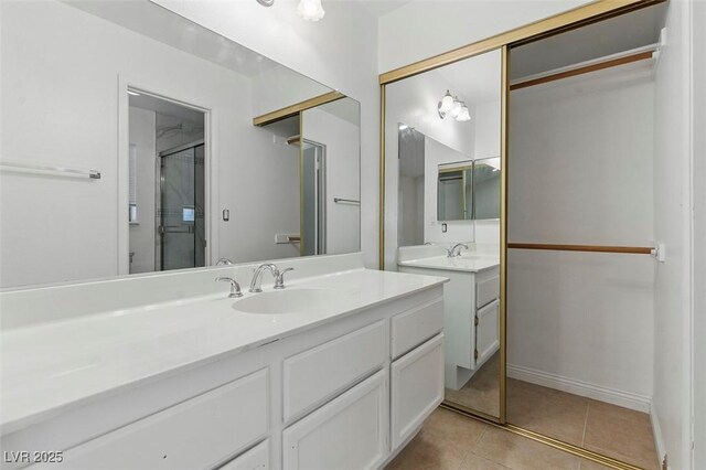 9116 Cypress Point Way, Las Vegas, NV 89117 - bathroom with two vanities, a stall shower, tile patterned floors, and baseboards