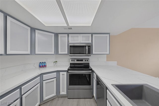 6250 W Flamingo Rd Unit 51, Las Vegas, NV 89103 - kitchen with appliances with stainless steel finishes, light wood-type flooring, light stone countertops, and glass insert cabinets