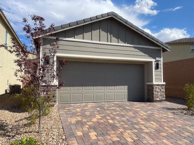 3447 SW Covilha Ln, Henderson, NV 89044 - view of property exterior featuring board and batten siding, decorative driveway, stone siding, and an attached garage
