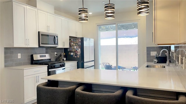 3447 SW Covilha Ln, Henderson, NV 89044 - kitchen with stainless steel appliances, a sink, a peninsula, decorative backsplash, and a breakfast bar area