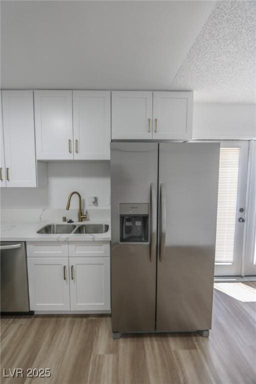 2711 Sesame Dr, Las Vegas, NV 89142 - kitchen with appliances with stainless steel finishes, a sink, light wood-type flooring, white cabinetry, and light countertops