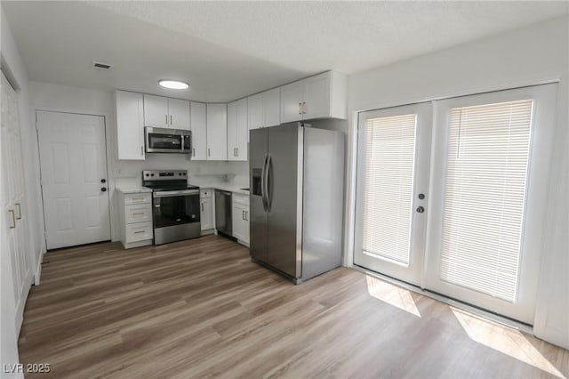 2711 Sesame Dr, Las Vegas, NV 89142 - kitchen featuring stainless steel appliances, wood finished floors, light countertops, white cabinetry, and french doors