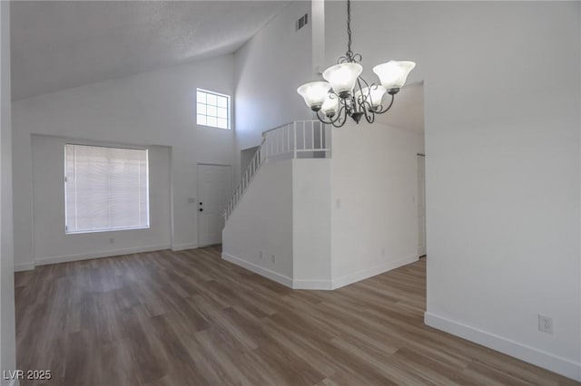 2711 Sesame Dr, Las Vegas, NV 89142 - unfurnished living room featuring a chandelier, high vaulted ceiling, wood finished floors, baseboards, and stairs