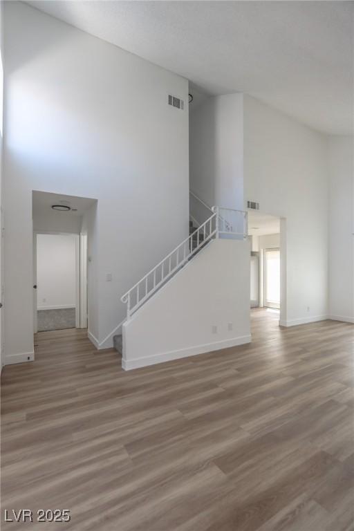 2711 Sesame Dr, Las Vegas, NV 89142 - unfurnished room with a high ceiling, light wood-style floors, baseboards, and stairs