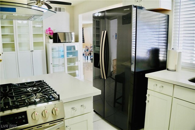 2659 Vegas Valley Dr, Las Vegas, NV 89121 - kitchen featuring fridge with ice dispenser, stainless steel gas stove, ceiling fan, light countertops, and white cabinetry