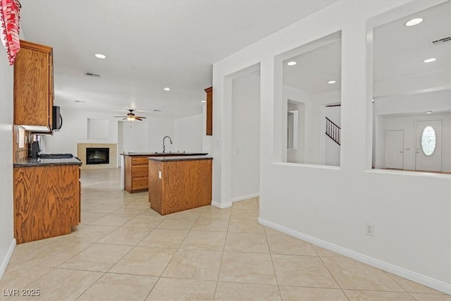 3689 Bufflehead St, Las Vegas, NV 89122 - kitchen featuring open floor plan, brown cabinets, a ceiling fan, recessed lighting, and a tile fireplace