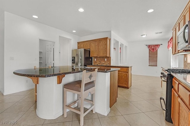 3689 Bufflehead St, Las Vegas, NV 89122 - kitchen with appliances with stainless steel finishes, backsplash, light tile patterned floors, a breakfast bar, and recessed lighting