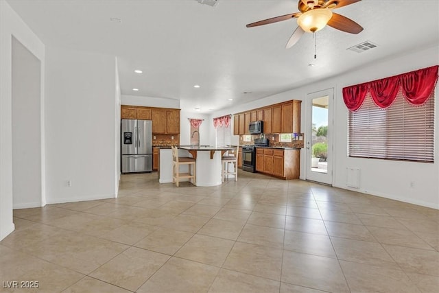 3689 Bufflehead St, Las Vegas, NV 89122 - kitchen with appliances with stainless steel finishes, light tile patterned floors, a breakfast bar area, recessed lighting, and brown cabinets