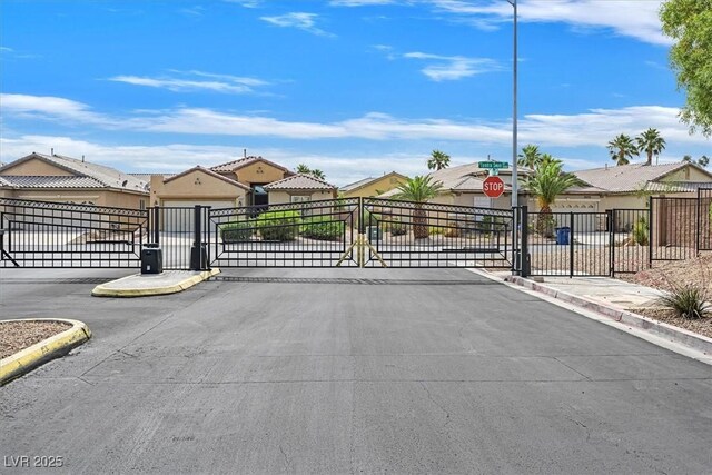 3689 Bufflehead St, Las Vegas, NV 89122 - view of asphalt road featuring a gate, traffic signs, curbs, and a gated entry