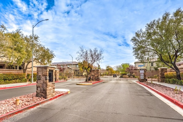 3725 Moonshine Falls Ave, North Las Vegas, NV 89085 - view of asphalt road featuring street lighting, curbs, a gate, and a gated entry