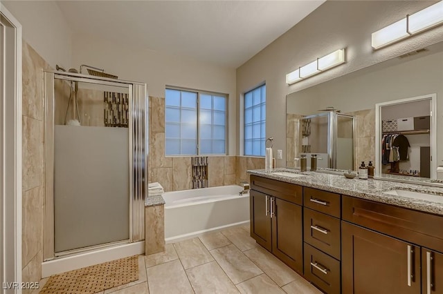 672 Solitude Point Ave, Henderson, NV 89012 - bathroom featuring a shower stall, a garden tub, double vanity, tile patterned flooring, and a walk in closet