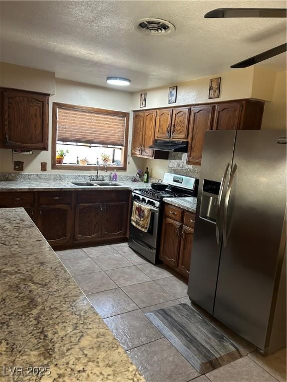 712 Donner St, Las Vegas, NV 89107 - kitchen with stainless steel appliances, a sink, range hood, a textured ceiling, and light tile patterned flooring