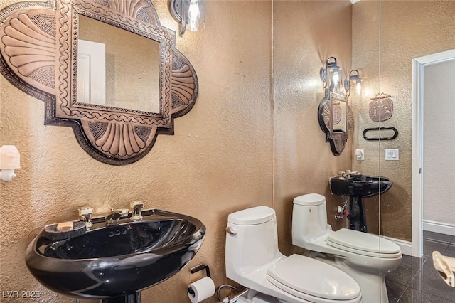 1609 Hidden Spring Dr, Las Vegas, NV 89117 - bathroom featuring toilet, a sink, granite tiled floors, baseboards, and a textured wall
