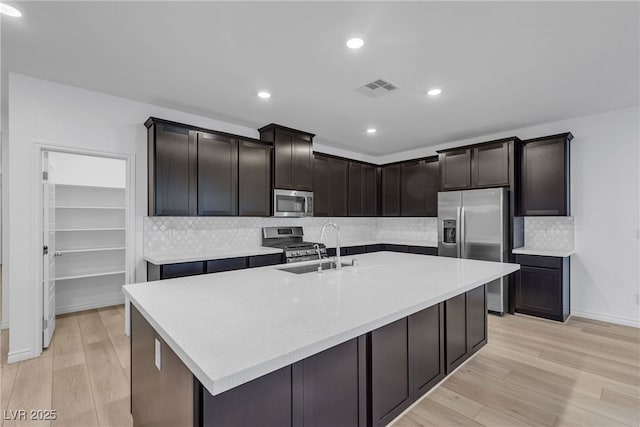 9570 Thistle Creek Ave, Las Vegas, NV 89178 - kitchen featuring stainless steel appliances, a sink, light wood-style flooring, light countertops, and backsplash