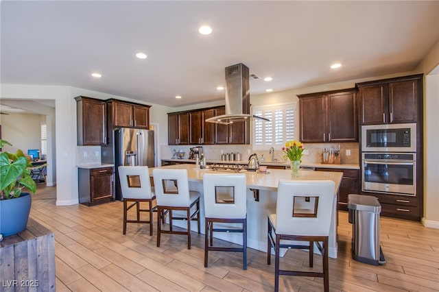 8298 W Agate Ave, Las Vegas, NV 89113 - kitchen featuring stainless steel appliances, island range hood, dark brown cabinets, light countertops, and recessed lighting