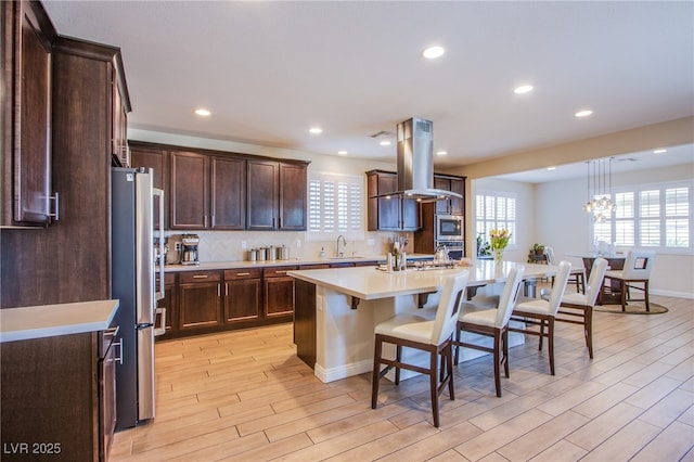 8298 W Agate Ave, Las Vegas, NV 89113 - kitchen with island range hood, stainless steel appliances, a kitchen bar, light countertops, and light wood finished floors