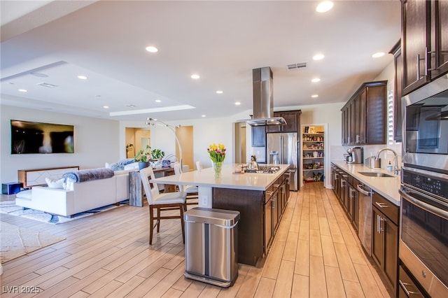 8298 W Agate Ave, Las Vegas, NV 89113 - kitchen with island range hood, dark brown cabinets, light wood-style flooring, a kitchen breakfast bar, and recessed lighting