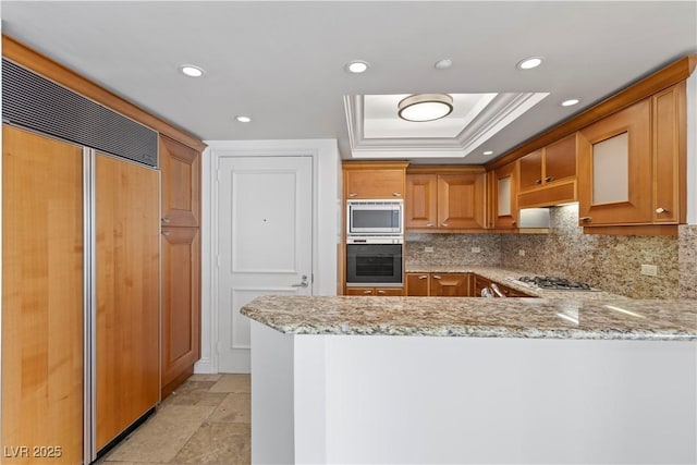 2777 Paradise Rd Unit 1002, Las Vegas, NV 89109 - kitchen featuring built in appliances, light stone countertops, a raised ceiling, backsplash, and recessed lighting