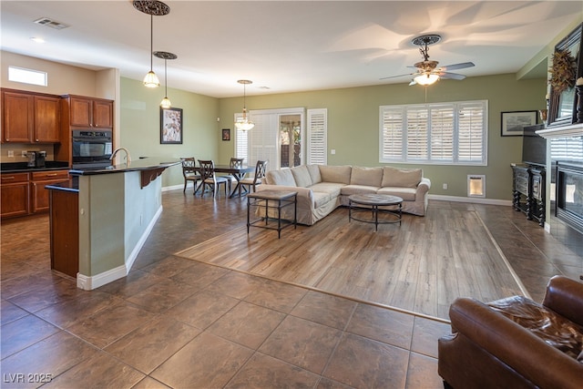 9077 Creed Mountain Pl, Las Vegas, NV 89178 - living area with baseboards, a glass covered fireplace, ceiling fan, and dark tile patterned flooring