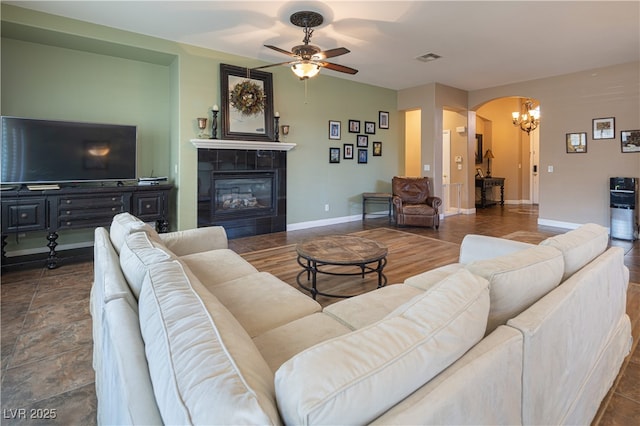 9077 Creed Mountain Pl, Las Vegas, NV 89178 - living area featuring arched walkways, a ceiling fan, a tile fireplace, baseboards, and a chandelier